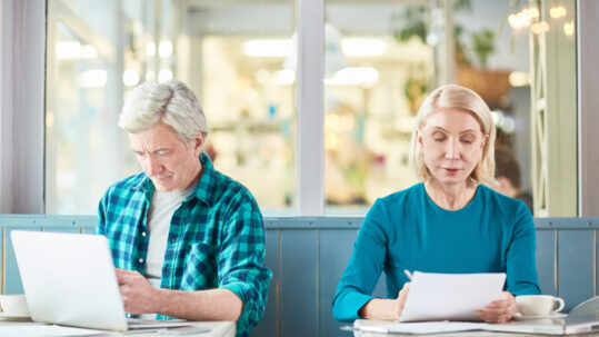 Older adults working on a laptop and reviewing paperwork, illustrating working in retirement and the Social Security earnings test.