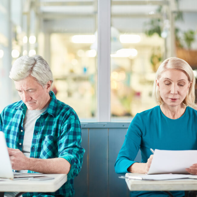 Older adults working on a laptop and reviewing paperwork, illustrating working in retirement and the Social Security earnings test.