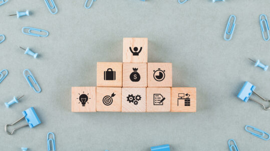 Wooden blocks with business icons representing tax-efficient employee benefits, retirement plans, and financial planning for small businesses
