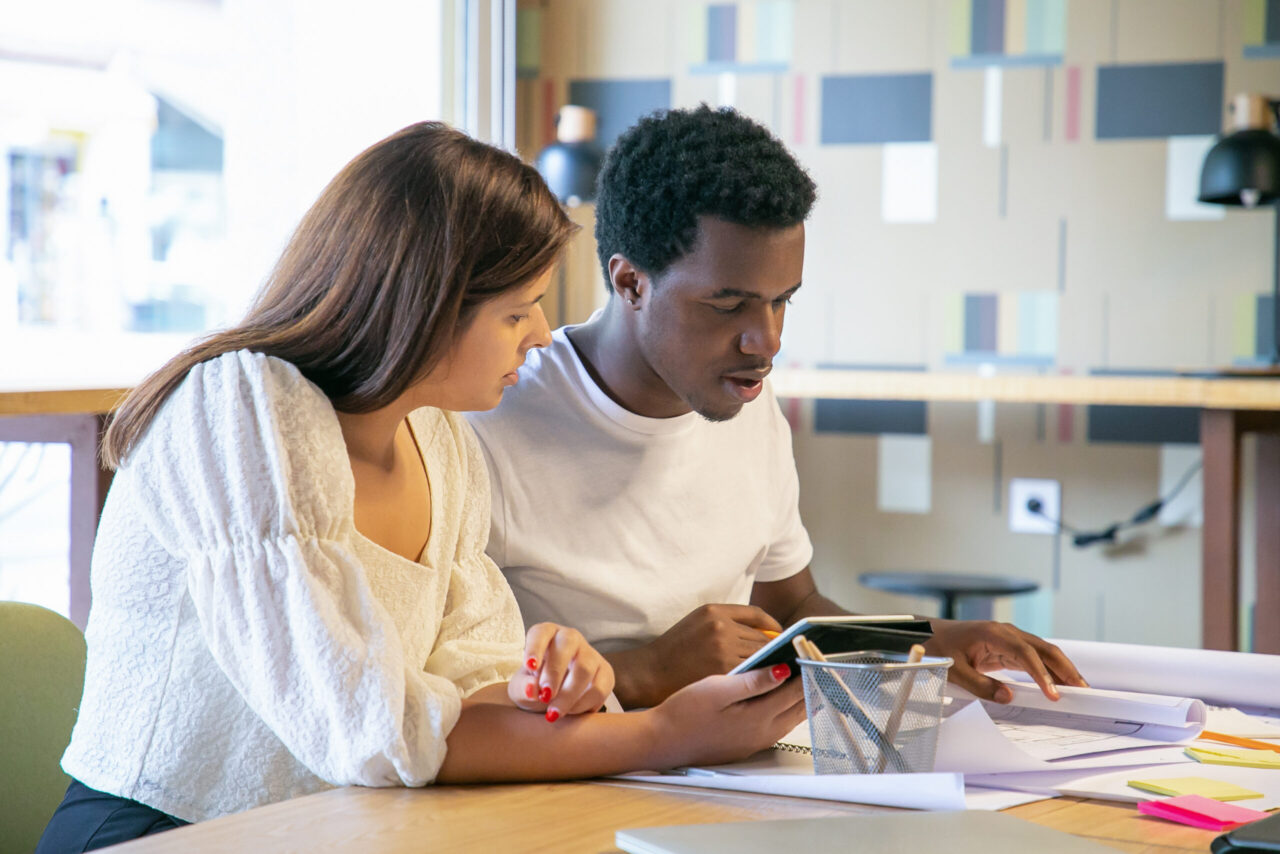 Young adults reviewing financial documents and a tablet while planning for education expenses