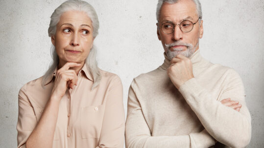 Older couple looking thoughtful and uncertain, illustrating the emotional challenges of investment decisions and market volatility.