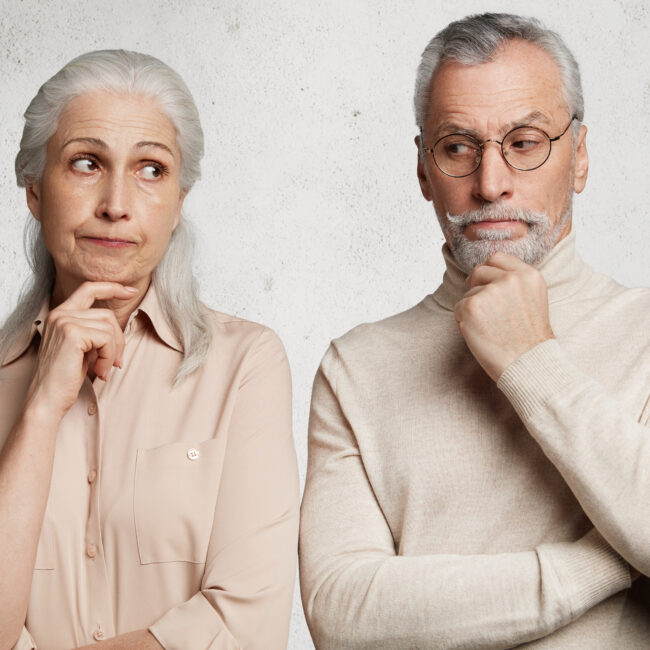 Older couple looking thoughtful and uncertain, illustrating the emotional challenges of investment decisions and market volatility.