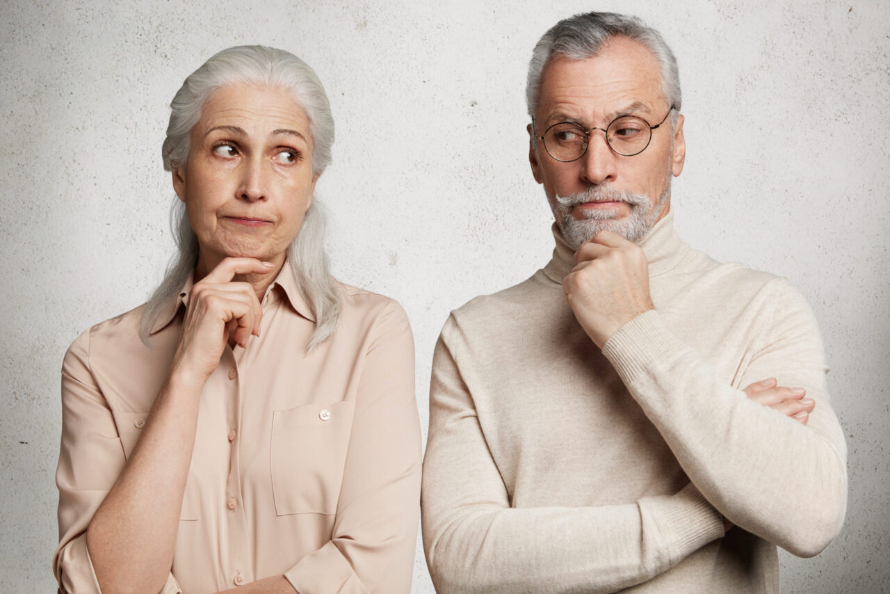 Older couple looking thoughtful and uncertain, illustrating the emotional challenges of investment decisions and market volatility.